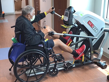 Man using a total body exerciser in a therapy gym.